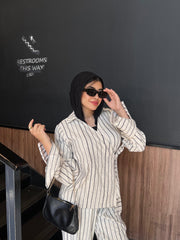 Woman in a striped outfit standing in front of a blackboard with 'Restrooms This Way' sign.